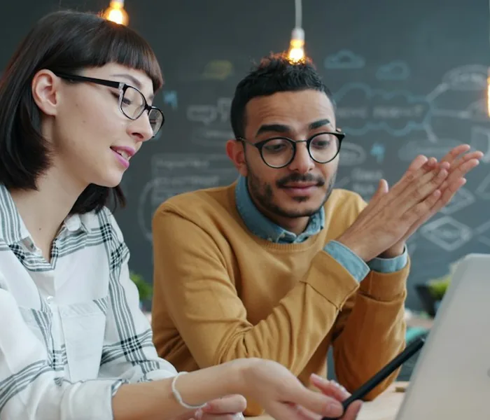 Two colleagues reviewing work at a laptop
