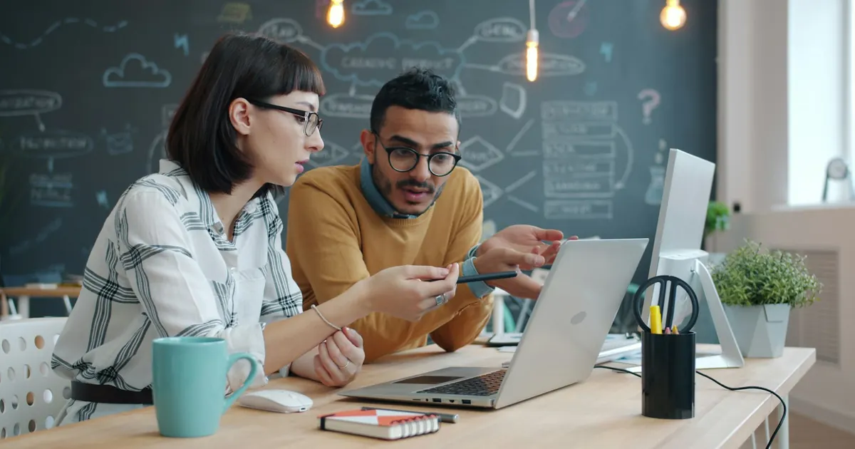 Two colleagues discussing work on a laptop