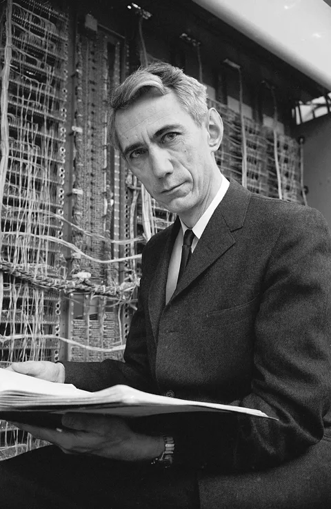 Claude Shannon beside electronic equipment