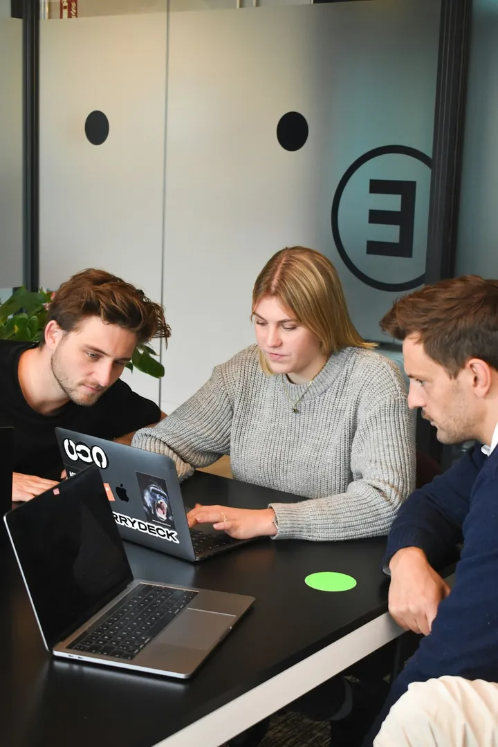 Three colleagues reviewing work together on a laptop